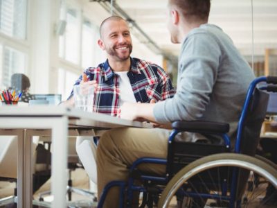 Handicap businessman discussing while sitting with colleague in creative office Handicap businessman discussing while sitting with colleague in creative office